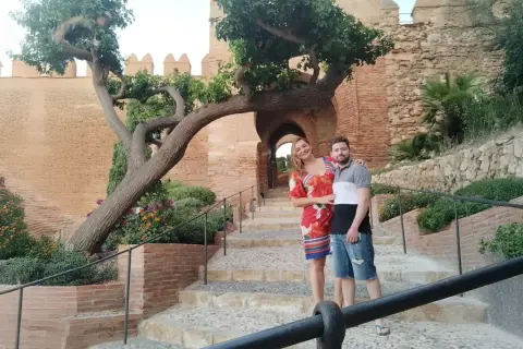 Pareja posando en escalinatas de piedra con un árbol retorcido y murallas de cañarete Almería de fondo.