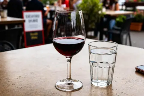 Un verre à vin rouge et un verre à eau sur une table de terrasse.