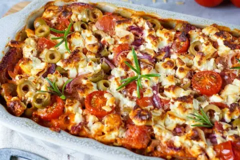 Herzhafter Kritharaki Auflauf mit Feta, Oliven, Tomaten und Rosmarin, goldbraun gebacken.