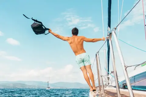 Uomo con zaino in barca a vela, un esempio di come vestirsi in barca a vela: costume e libertà.
