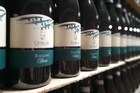 Bottiglie di vini oltrepò pavese, Riesling Brina, in fila su uno scaffale.