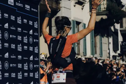 La coureuse Camille, dossard 30, lève les bras en signe de victoire à l'UTMB. Une scène qui a suscité une vive polémique.