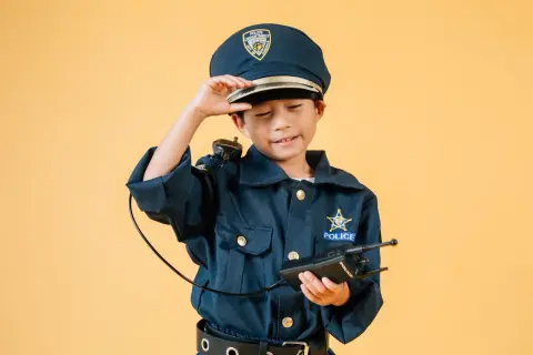 Dziecko w stroju policjantki, z czapką i krótkofalówką, gotowe do akcji.