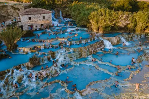 Cascate termali con gente che si rilassa. Per sapere come arrivare alle terme di Saturnia, guarda questa meraviglia naturale.