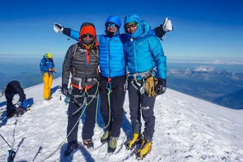 Drei Bergsteiger auf dem Gipfel des Monte Blanc, umgeben von Schnee und einer atemberaubenden Aussicht.