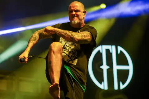 Phil Anselmo z Pantery w Polsce, z mikrofonem w dłoni, na tle sceny z oświetleniem.