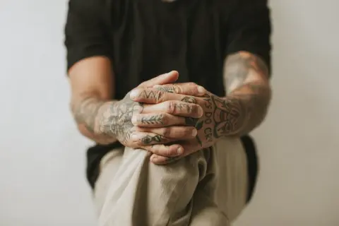 Dłonie z tatuażami wykonanymi metodą handpoke, z widocznym napisem "BOYS DO CRY".