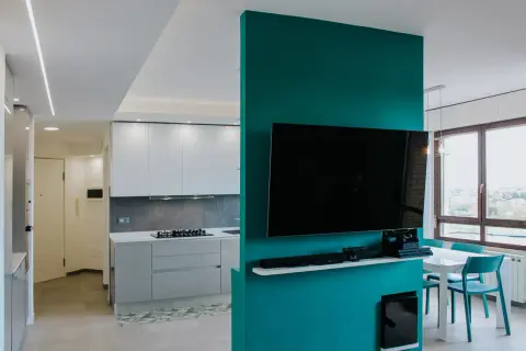 Un moderno cartongesso open space divide cucina e zona living con TV. Luce soffusa e colori vivaci.