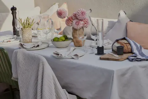 En vacker dukning utomhus med blommor, ljus och nybakat bröd. En inbjudande scen för en somrig middag.