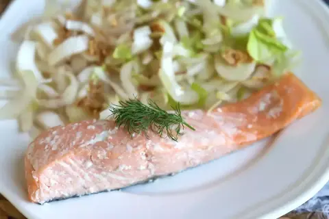 Un délicieux pavé de saumon rose, garni d'aneth frais, servi avec une salade croquante de fenouil et d'oignons.