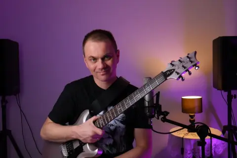 Mężczyzna z gitarą elektryczną, gotowy do nauki gry na gitarze online za darmo.