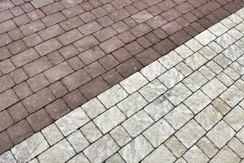 Pavimentazione esterna con blocchi di cemento color tortora e grigio chiaro, disposti a spina di pesce.