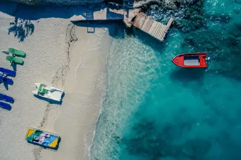 Widok z lotu ptaka na plażę z łodziami i turkusową wodą. Golem Albania atrakcje to idealne miejsce na wakacje.