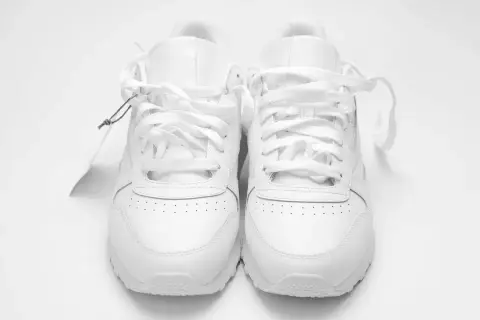 Un paio di scarpe da ginnastica bianche, nuove di zecca, con etichetta. Chissà a quanti gradi si lavano le scarpe per mantenerle così immacolate.