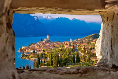 Vista incantevole del castello di Malcesine affacciato sul lago, con montagne sullo sfondo.