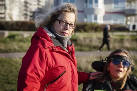 Catrin Hedlund Seyhan med handen på en kvinna i rullstol utomhus.