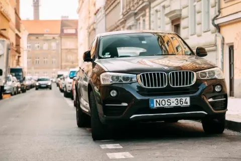 Czarny SUV zaparkowany na ulicy, przypominający o przepisach dotyczących zastawiania bramy wjazdowej.