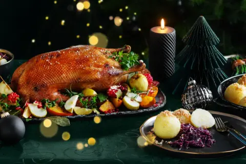 Festliches weihnachtsessen einen tag vorher vorbereiten: goldbraune Gans mit Früchten, Klößen und Rotkohl, Kerzenlicht und Weihnachtsdeko.