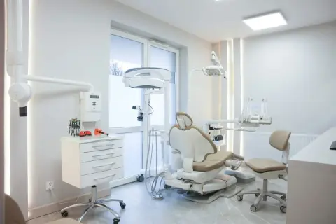 Nowoczesny gabinet stomatologiczny z fotelem dentystycznym i sprzętem medycznym.
