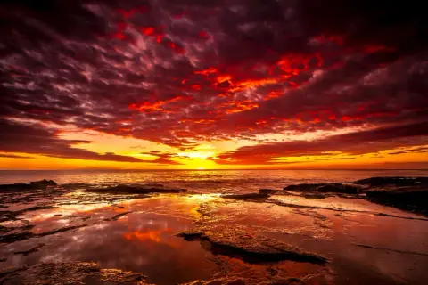 Coucher de soleil spectaculaire avec des nuages rougeoyants. Quel filtre ND pour coucher de soleil aurait pu capturer cette intensité ? La mer reflète les couleurs flamboyantes.