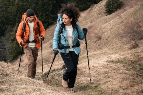 Para trekking w górach, ważne są odpowiednie **końcówki do kijków w góry**. Para turystów w odzieży outdoorowej pokonuje górski szlak.