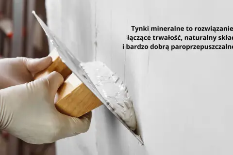 Ręce w rękawiczkach nakładają tynk na ścianę kielnią. To obrzutka, która zapewnia trwałość i paroprzepuszczalność.