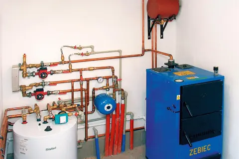 Instalacja grzewcza z kotłem, zasobnikiem i pompami obiegowymi. System zapewnia ogrzewanie podłogowe i grzejniki na jednym obiegu.