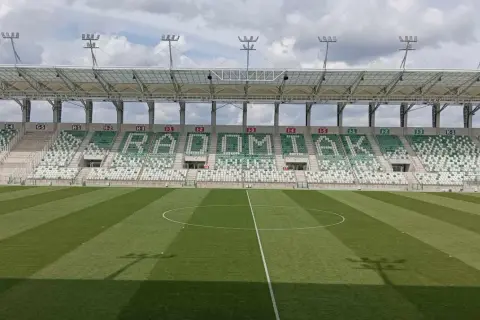 Puste trybuny stadionu RKS Radomiak Radom z napisem "RADOMIAK" ułożonym z zielonych i białych siedzeń.