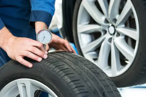Un meccanico misura il battistrada di uno pneumatico 4 stagioni per capire quanti km fanno ancora.
