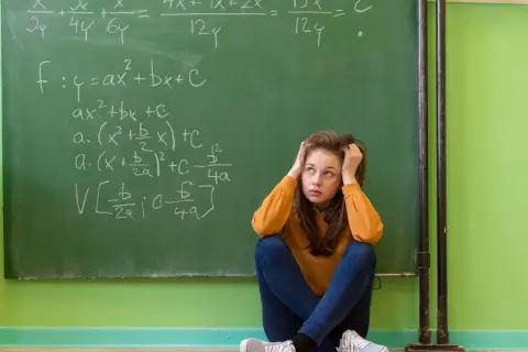 Dziewczyna zmagająca się z zadaniami matematycznymi na tablicy, symbolizująca dyskalkulię u dorosłych.