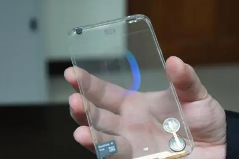 Dłoń trzyma przezroczysty telefon, który wygląda jak szklany. Widać w nim niebieski okrąg i kartę pamięci.