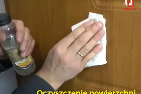 Rysy na drzwiach z okleiny znikają dzięki czyszczeniu. Dłoń z pierścionkiem przeciera powierzchnię.