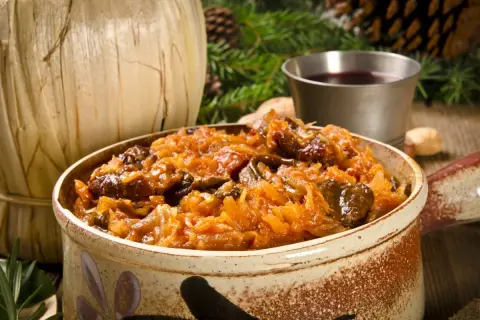 Aromatyczny bigos z różnymi rodzajami mięsa, serwowany w glinianym naczyniu, idealny na zimowe wieczory.