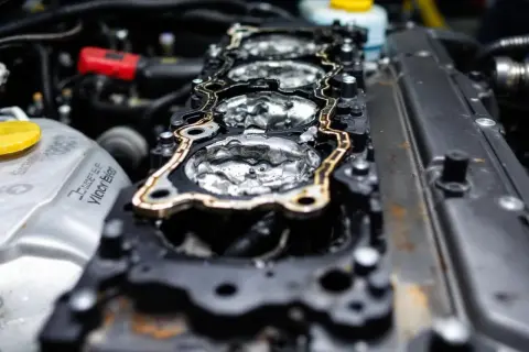 Joint de culasse endommagé, signe d'une fuite de liquide de refroidissement. L'intérieur du moteur est visible, avec des traces d'humidité.