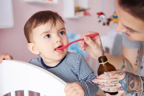 Mama podaje dziecku witaminę D na łyżeczce. Ważne jest, ile witaminy D dla 2 latka, by zapewnić mu zdrowy rozwój.