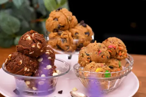 Tre skålar med olika sorters cookie dough recept: choklad med vita chokladknappar, klassisk med chokladknappar och en med färgglada godisbitar.