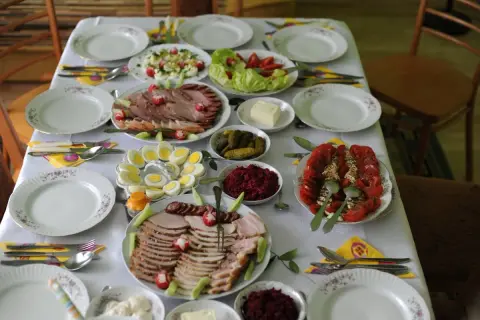 Stół zastawiony pysznymi przystawkami wielkanocnymi na zimno: wędliny, jajka, sałatki, buraczki i pomidory.