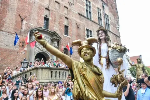 Złoci aktorzy na jarmarku świętego dominika w Gdańsku, tłum widzów z aparatami.