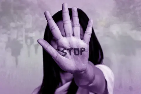 Mano extendida con la palabra "STOP" escrita, simbolizando cómo ayudar a una mujer maltratada.