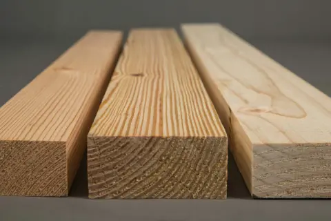 Tres tablones de diferentes tipos de madera de pino, mostrando sus vetas y nudos característicos.