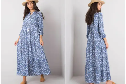 Modelka prezentuje zwiewną, błękitną sukienkę w drobne kwiatki, idealną dla kobiet plus size. Długi fason i falbany dodają jej lekkości.