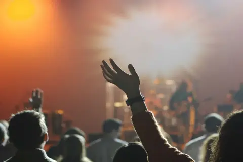 Menschen mit erhobenen Händen in einem Gottesdienst. Sie sind Teil der Pfingstbewegung, die sich durch lebendige Anbetung auszeichnet.