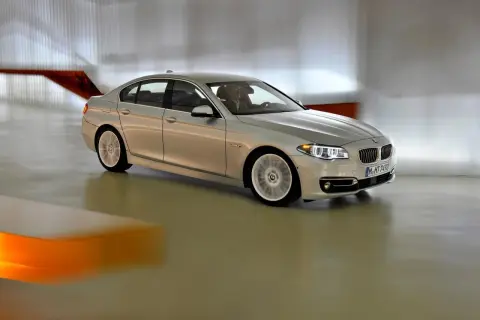 Srebrne bmw f10 lift w ruchu, z rozmytymi kołami, porusza się po nowoczesnym wnętrzu.
