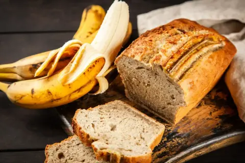 Pyszne ciasto z bananami, obok leżą dojrzałe banany. Idealne na deser lub śniadanie.