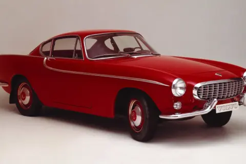 Une élégante Volvo rouge, un modèle emblématique des années 50, se dresse fièrement sur un fond neutre.