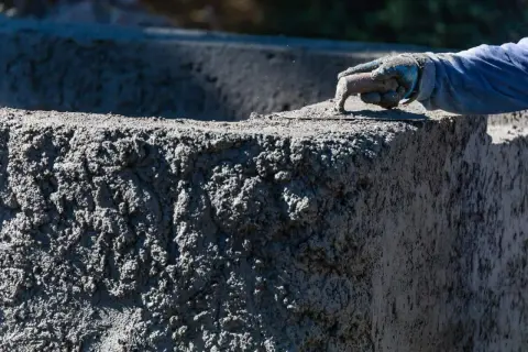 Ręka w rękawicy wygładza świeży beton B20. Sprawdzamy beton B20 cena za m3.