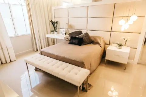 Elegancka sypialnia z tapicerowanym zagłówkiem, który pokazuje, jak zamontować panele tapicerowane na ścianie. Jasne kolory i minimalistyczne meble tworzą przytulną atmosferę.