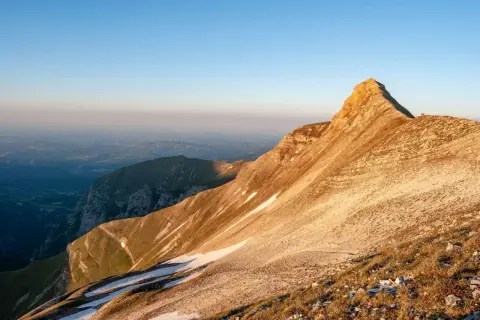 Alba dorata sulla Sibilla Appenninica, con valli nebbiose e un rifugio solitario in vetta.
