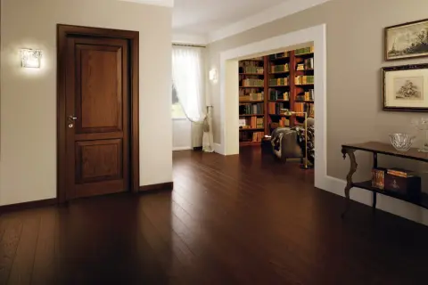 Un elegante corridoio con un battiscopa diverso dalle porte in legno scuro, che conduce a una biblioteca ricca di libri.