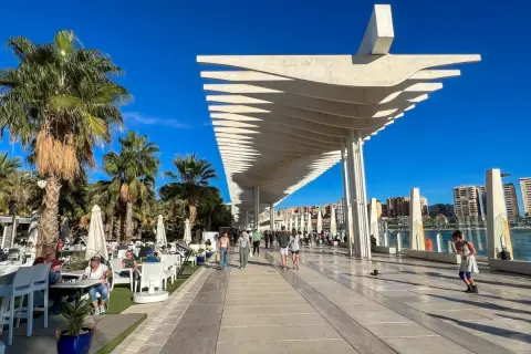 Spacerem po Muelle Uno w Maladze, gdzie zobaczyć można nowoczesną architekturę i palmy.